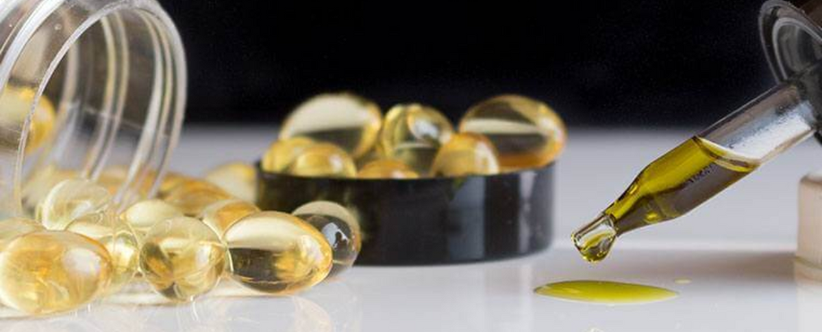 Close-up of hemp oil capsules and dropper on a white surface