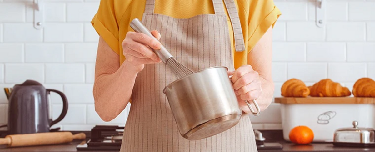 Person whisking in a pot while cooking in a kitchen setting