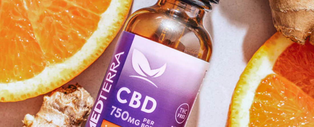 Bottle of Medterra CBD tincture labeled 'CBD 750MG PER BOTTLE THC FREE' surrounded by orange slices and ginger root.