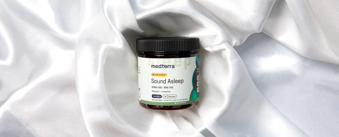 Medterra Sound Asleep CBD gummies jar on white silky fabric, label reads: "medterra, HIGH POTENCY, Sound Asleep, 50MG CBD - 5MG THC, Melatonin - L-theanine, Blueberry, 20 Gummies, HEMP SUPPLEMENT - 1000MG CBD & 100MG THC PER CONTAINER, FULL SPECTRUM".