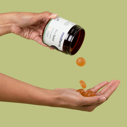 A person pours orange Max Relief Full Spectrum CBD Gummies from a black and white container into their hand. The container is labeled "Medterra" and "Max Relief." The background is a plain, light green color. These gummies feature Full Spectrum Hemp Extract to offer the entourage effect for enhanced wellness.