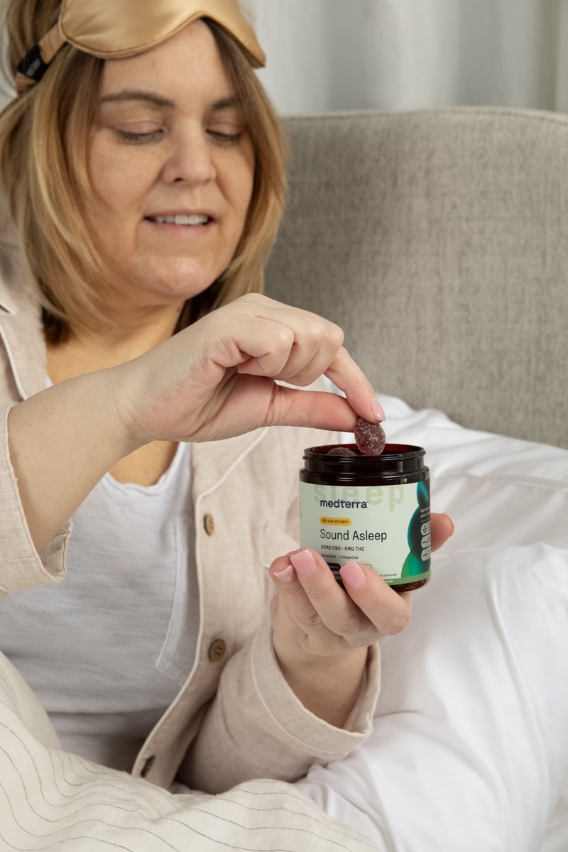 Woman taking a gummy from a jar of Medterra Sound Asleep